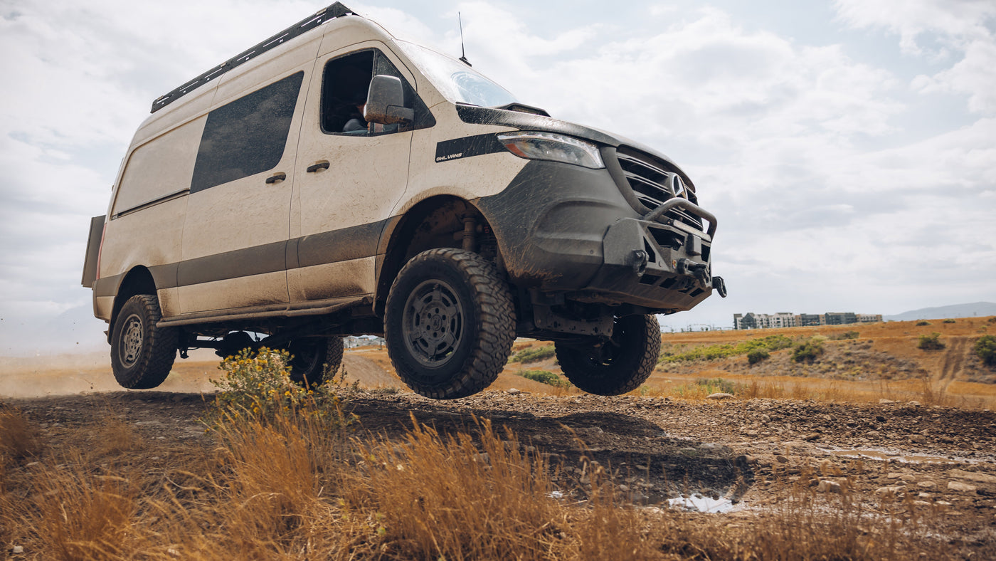 Van driving off-road on a dirt path with a clear sky