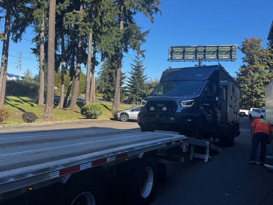 Winnebago EKKO on a Ford Transit arriving on a vehicle transport truck at Wolf Pack Overland