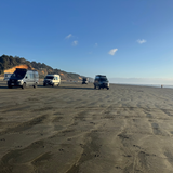 Four vans on a sandy beach with a clear blue sky.