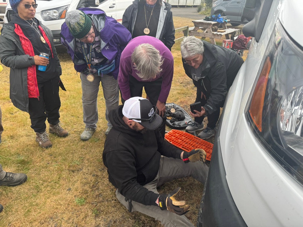 Hands-on tire-change instruction beside a Ford Transit