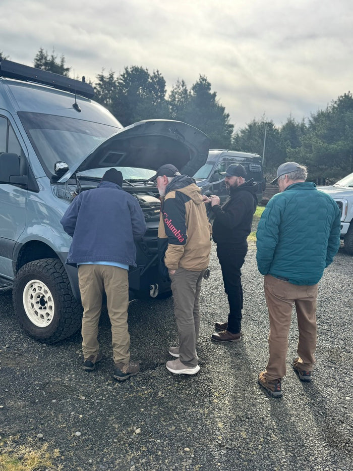 A group learning about their Ford Transit beside its open hood
